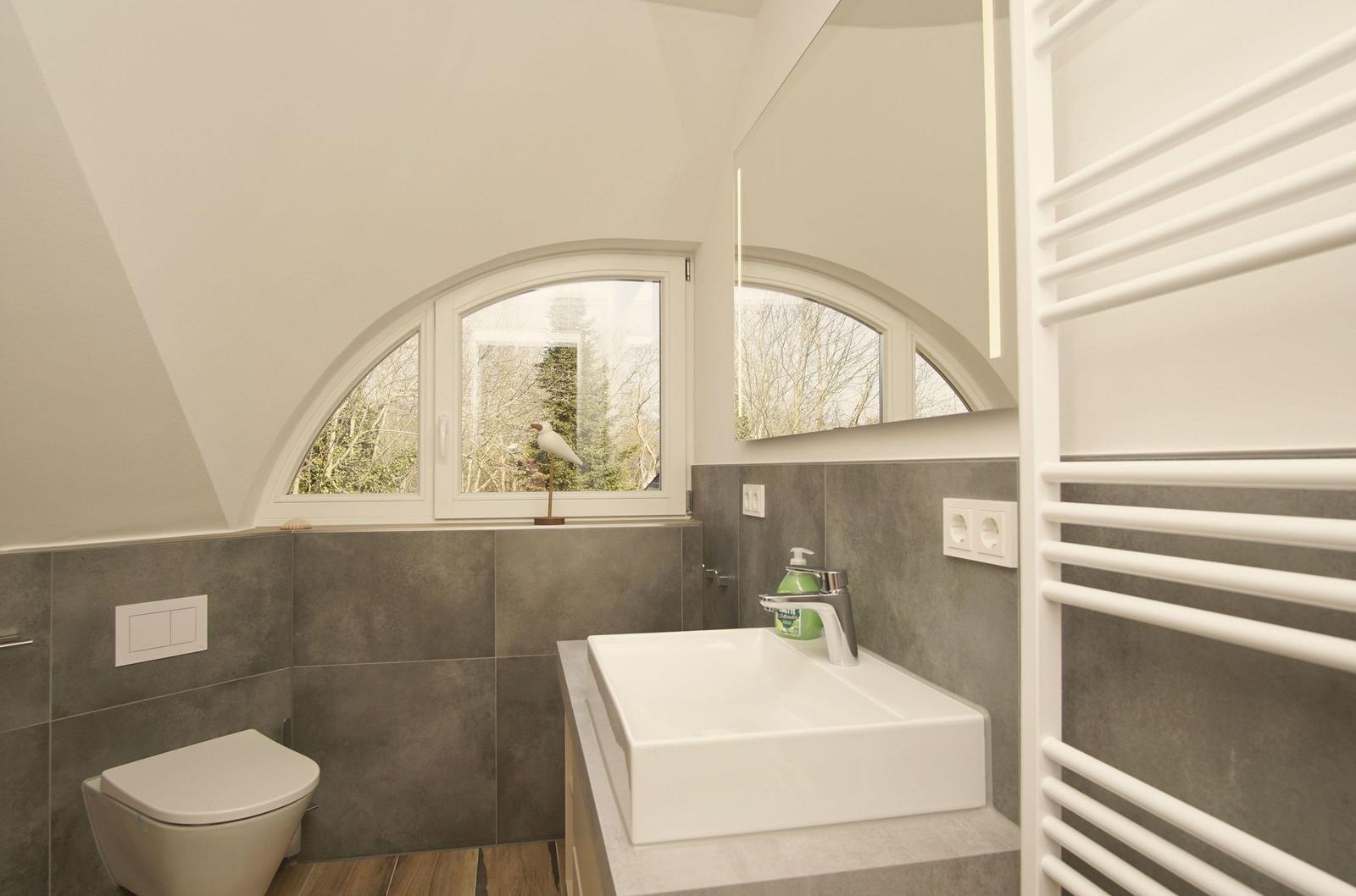 Badezimmer mit Waschbecken, Toilette und Badezimmerfenster