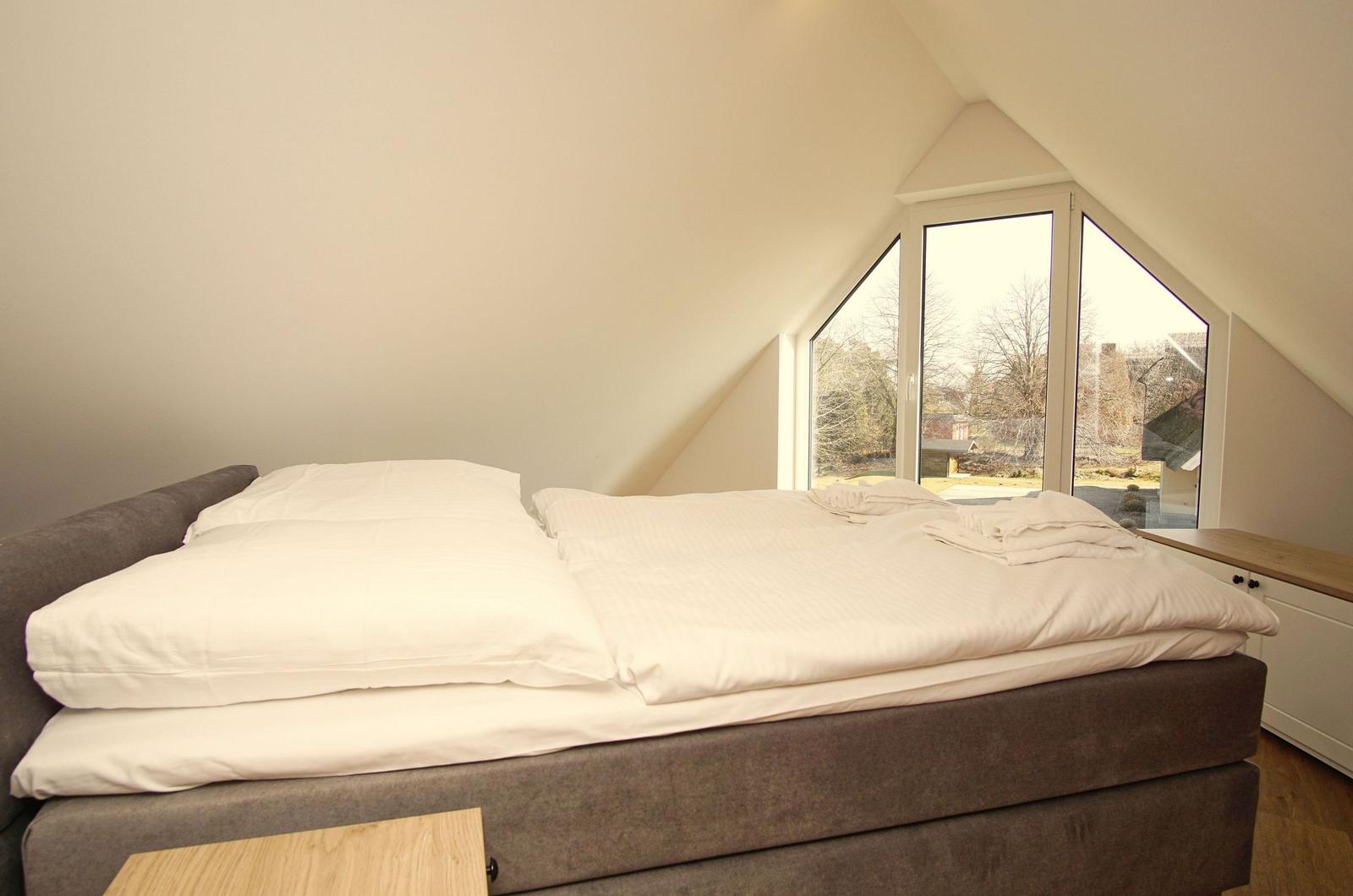 Schlafzimmer mit Doppelbett und großem Fenster zur Aussicht