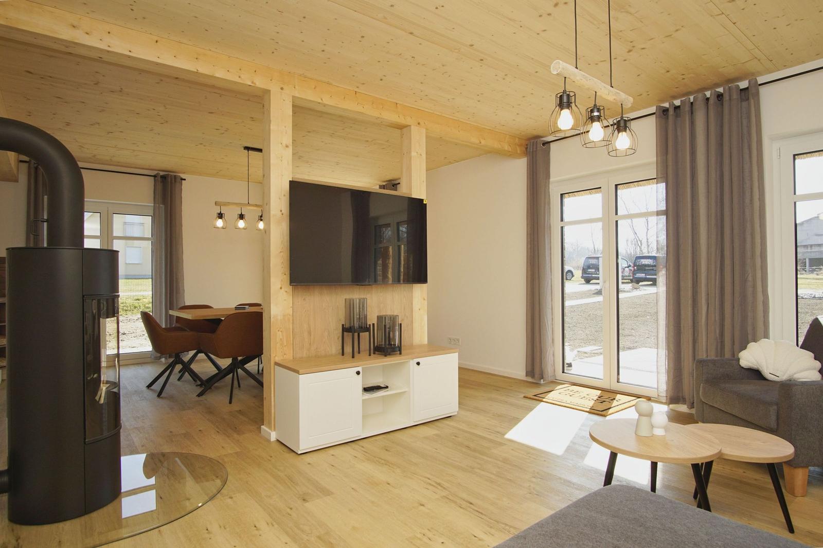 Wohnzimmer mit TV, Holzdecke und Kamin. Durchgang zur Essnische.