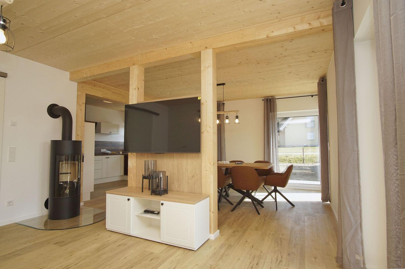 Wohn- und Essbereich mit Holzdecke, Kamin und TV.