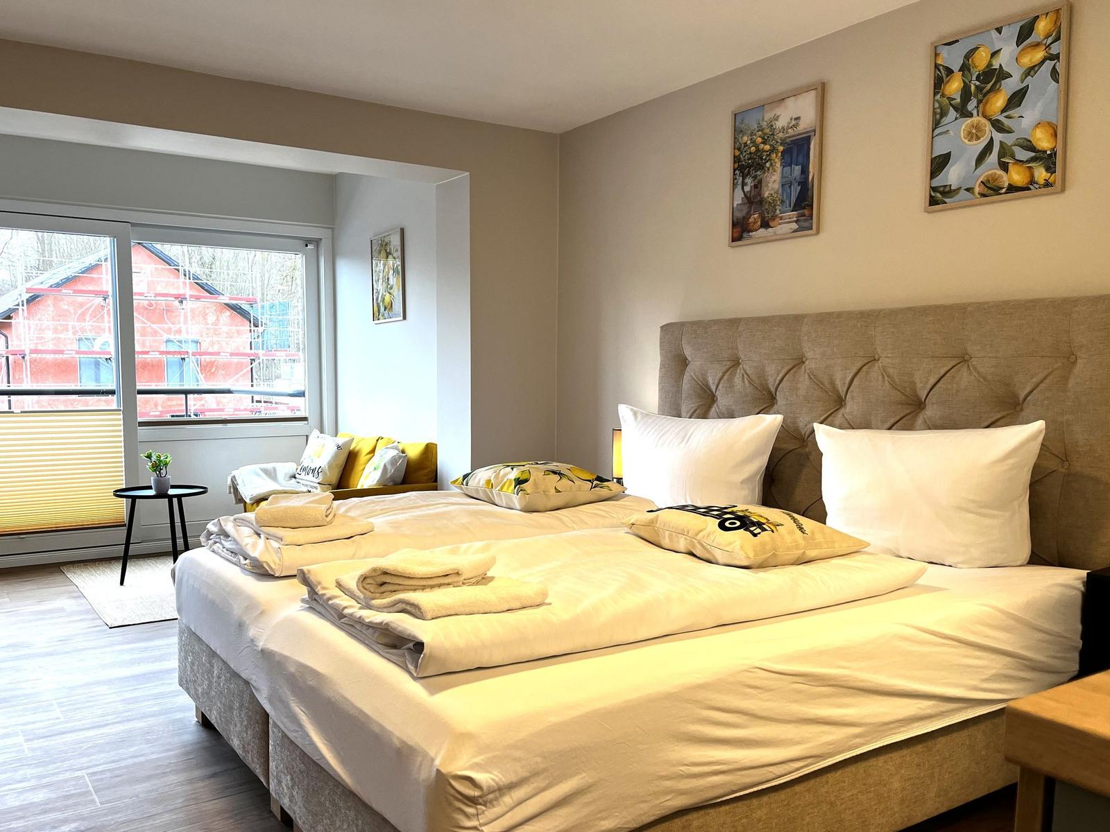 Doppelbett mit Kissen und Bettwäsche. Fenster mit Blick auf Außenbereich.