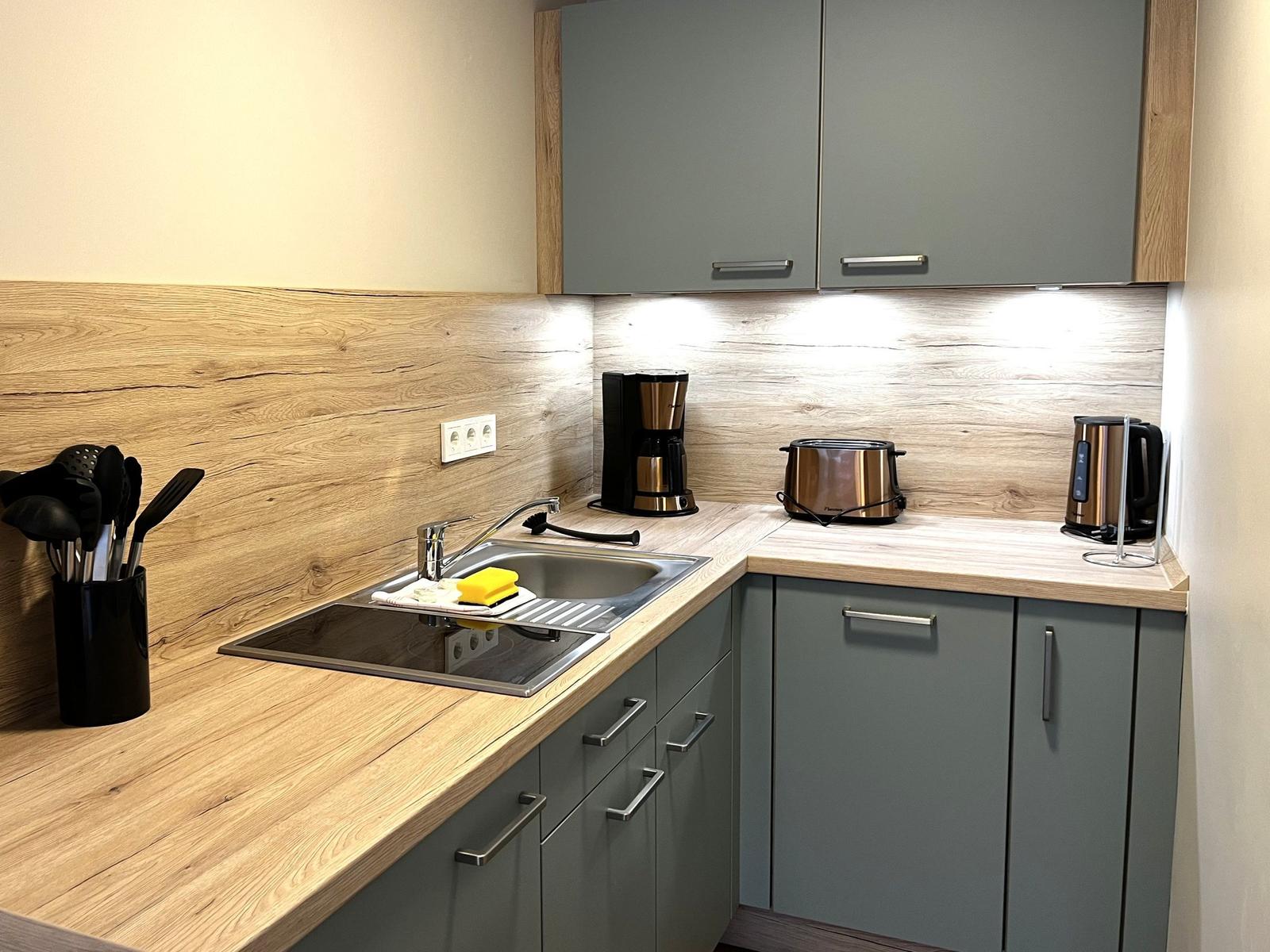 Küche mit Holz Arbeitsfläche, grauen Schränken und Küchengeräten.