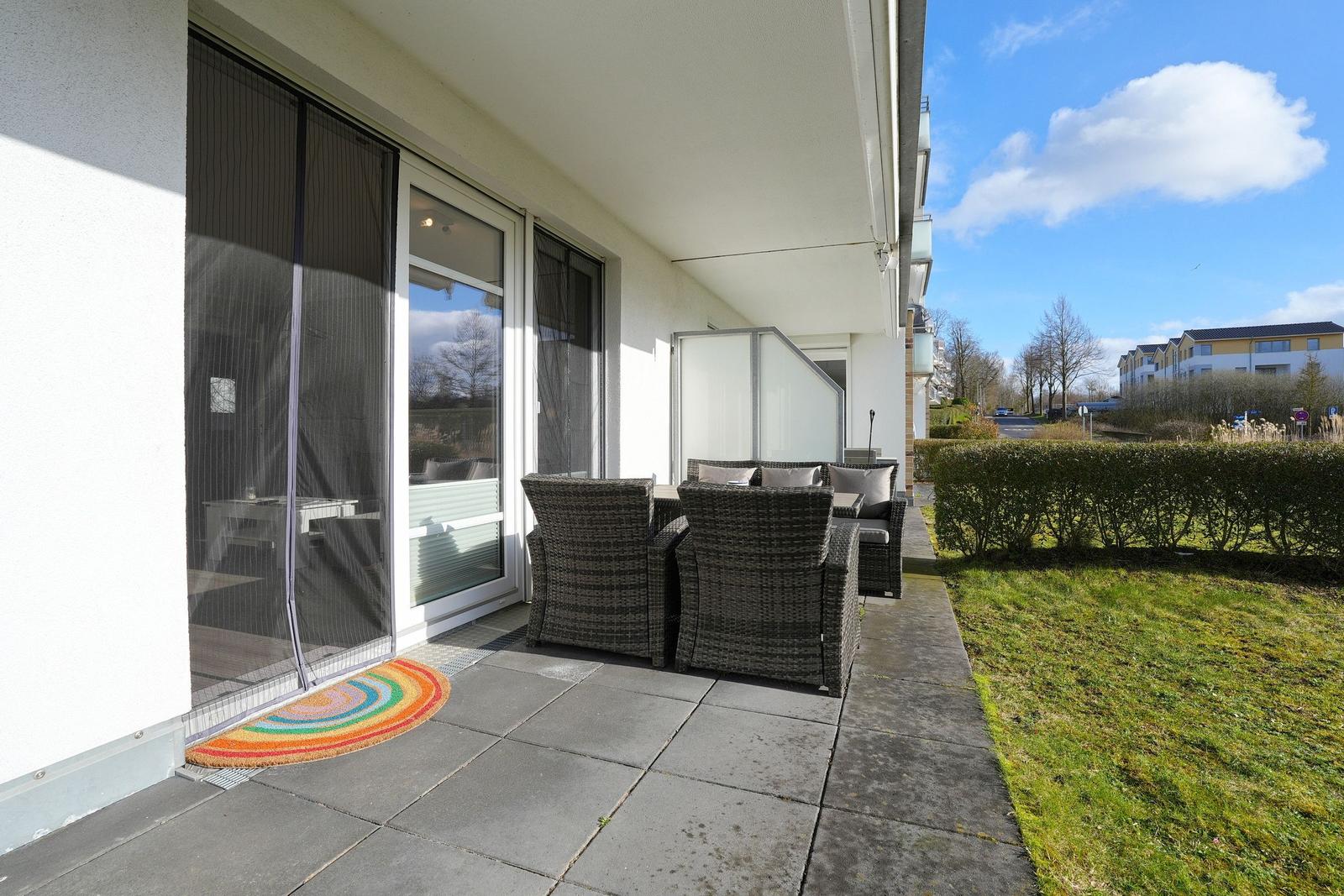 Terrasse mit Sitzgruppe und Glasfront. Regenbogenmuster vor Tür.