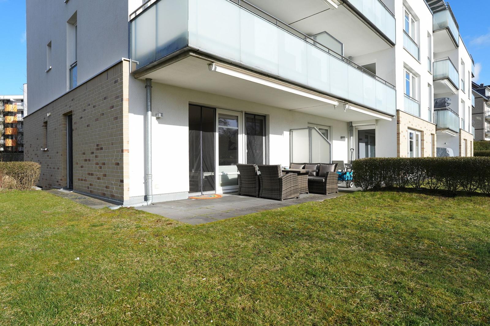 Terrasse mit Sitzgruppe und Garten vor modernem Haus
