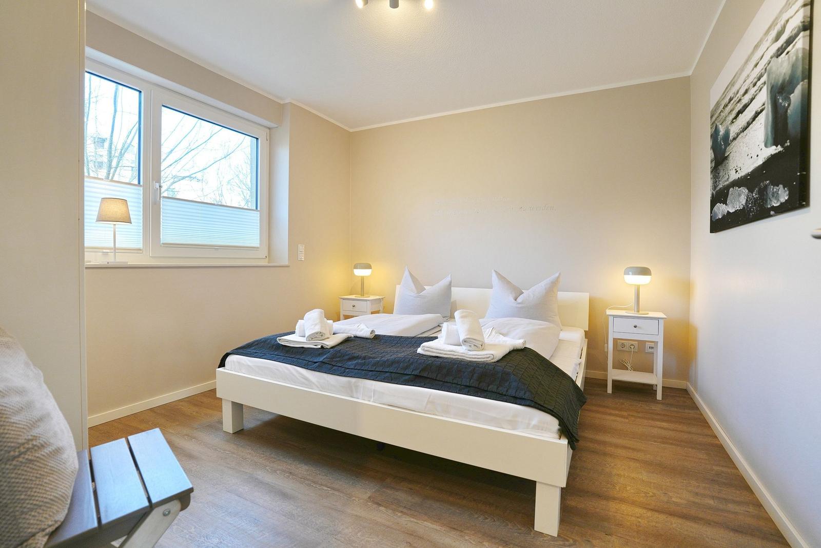 Schlafzimmer mit Bett, Nachttischen und Fenster