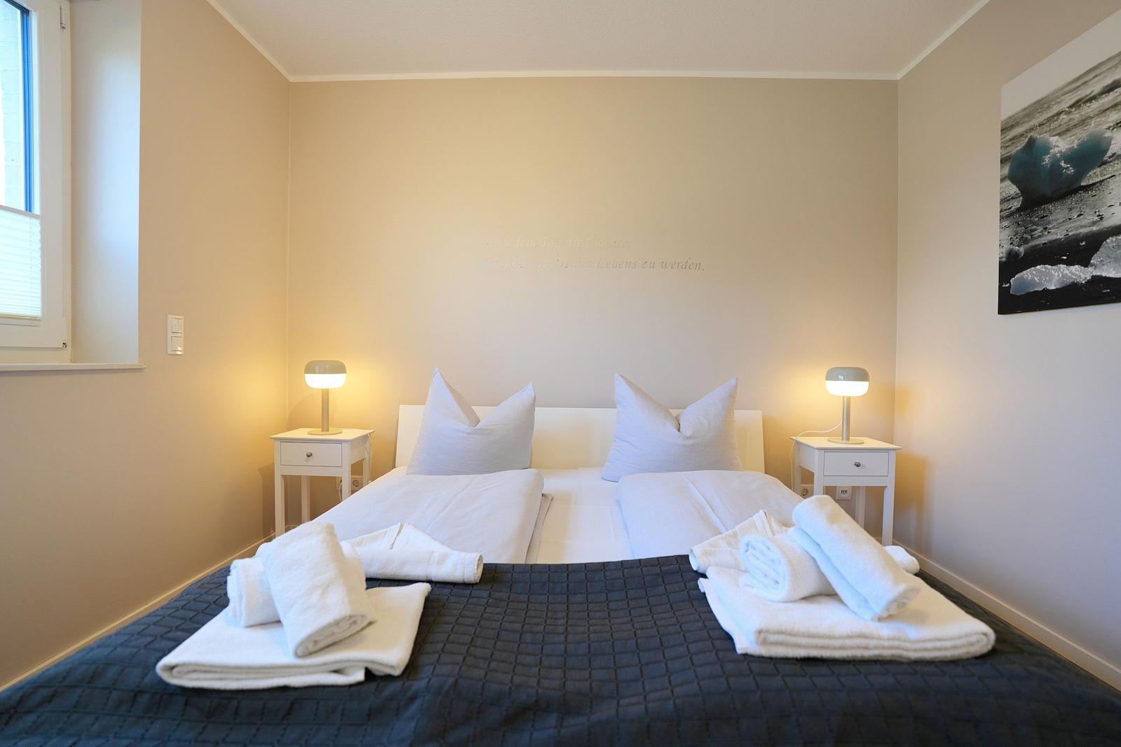 Schlafzimmer mit Doppelbett, zwei Nachttischen und Wandbild.