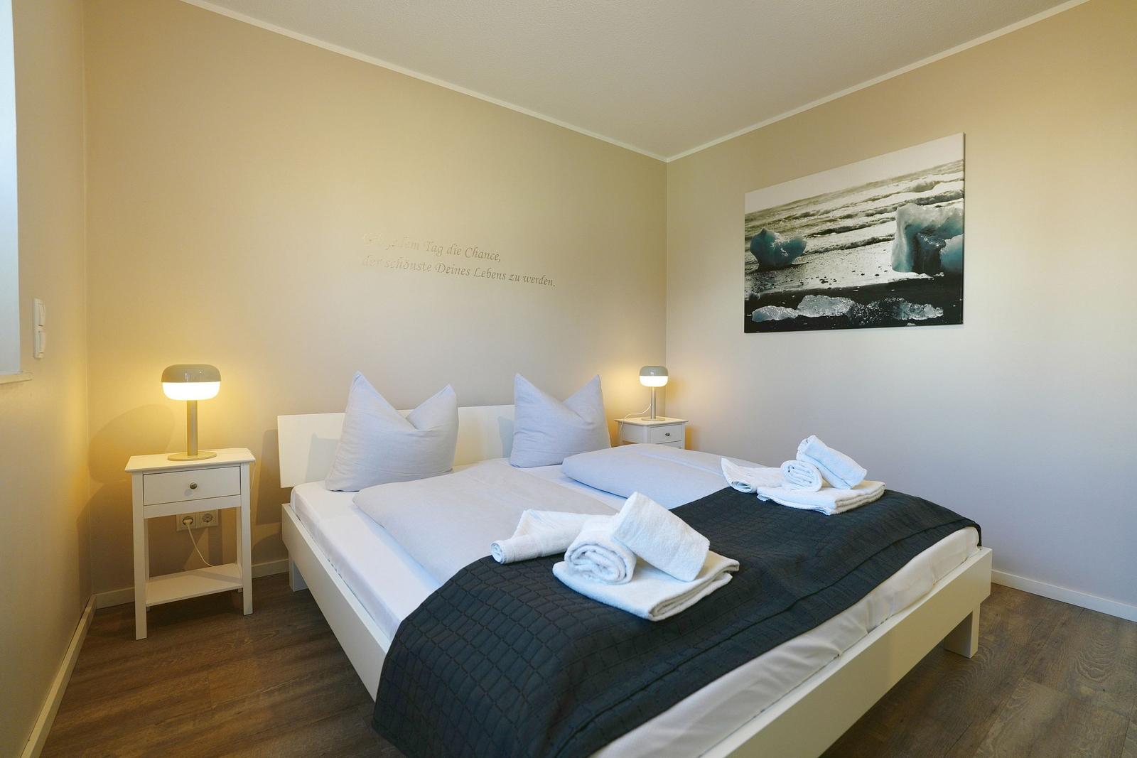 Schlafzimmer mit Bett, zwei Nachttischen und Wandbild.