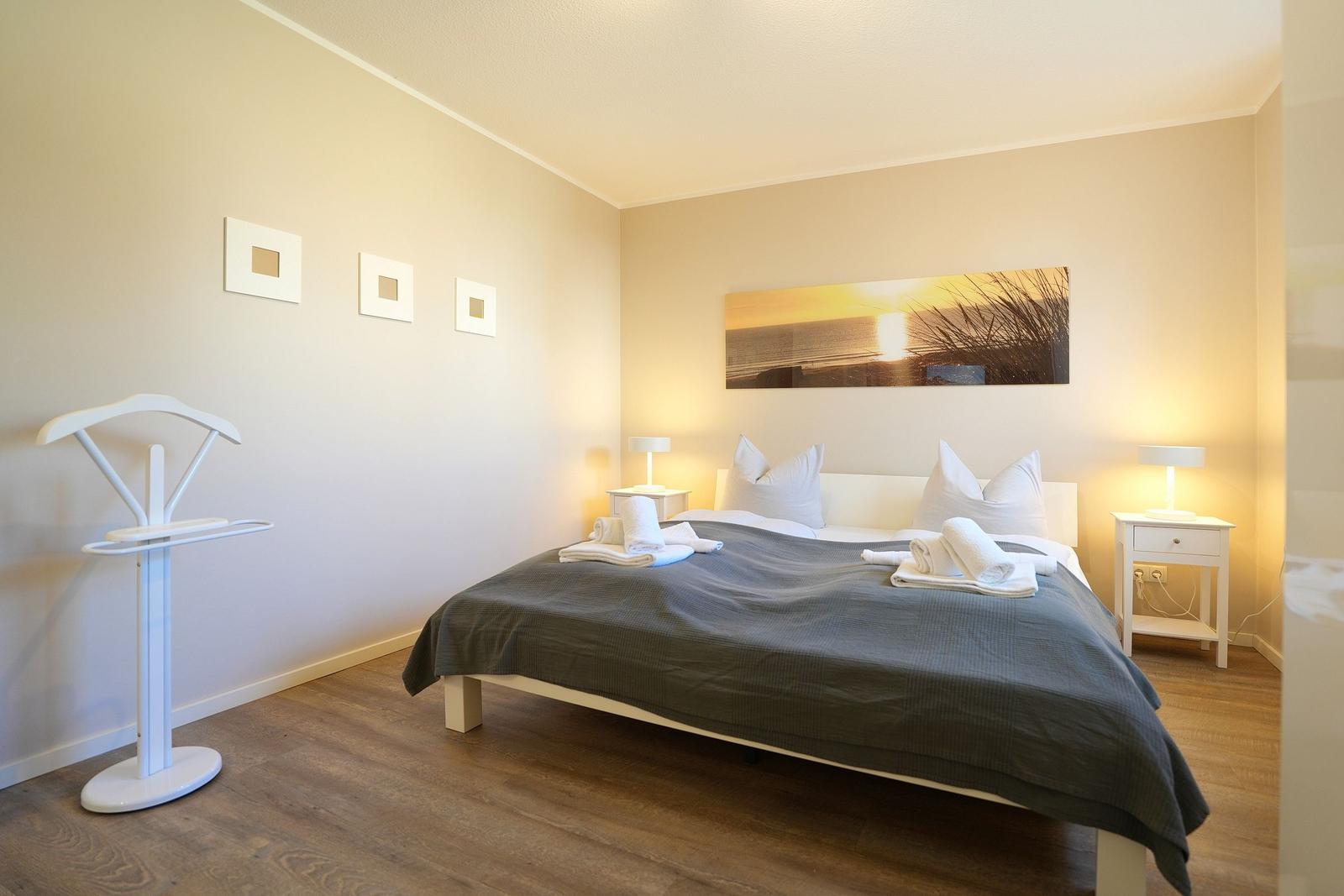 Schlafzimmer mit Bett, Nachttischen und Wandbild