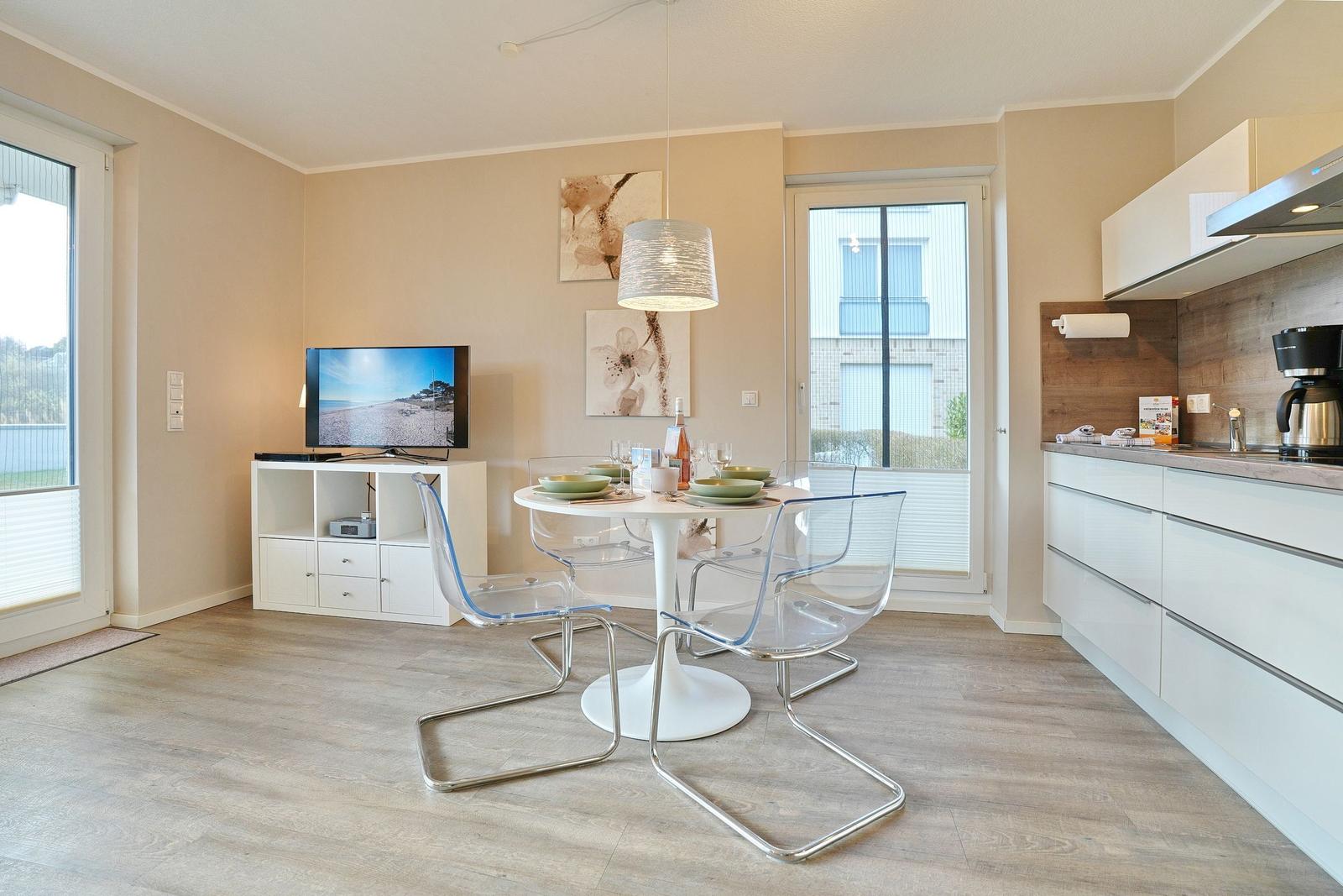 Wohn- und Essbereich mit Küche, TV und Essplatz.
