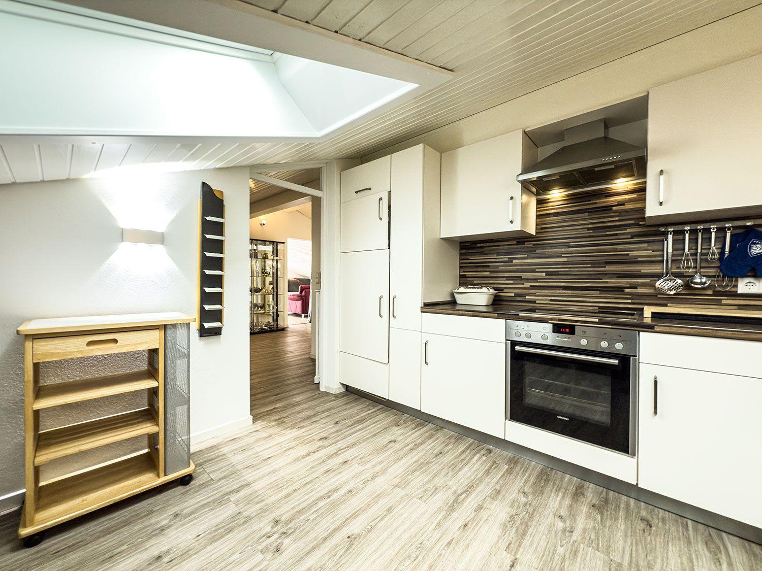 Küche mit weißen Schränken, Holzboden und Dunstabzug.
