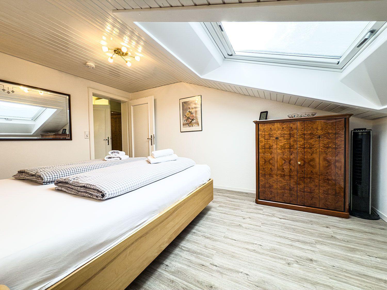 Schlafzimmer mit Dachschrägen, Dachfenster, Holzboden und Schrank.