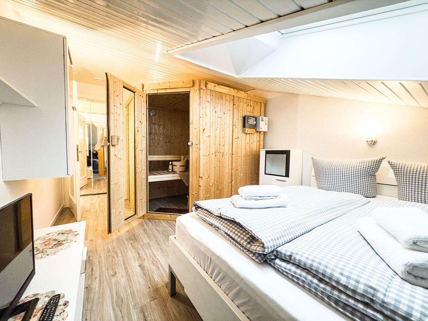 Schlafzimmer mit Bett, Sauna und TV.