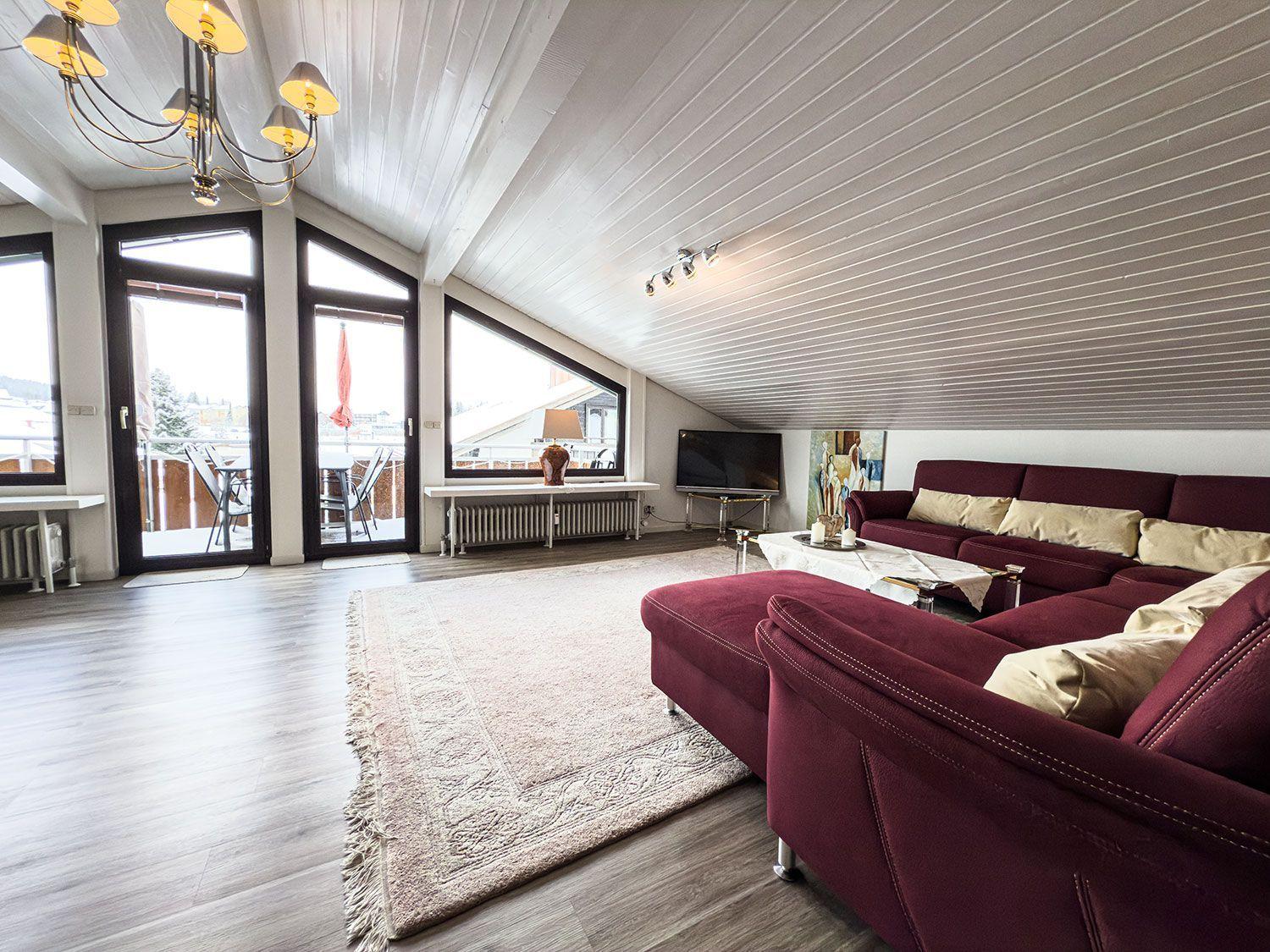 Wohnzimmer mit rotem Sofa, Glasboden und großen Fenstern zur Terrasse.