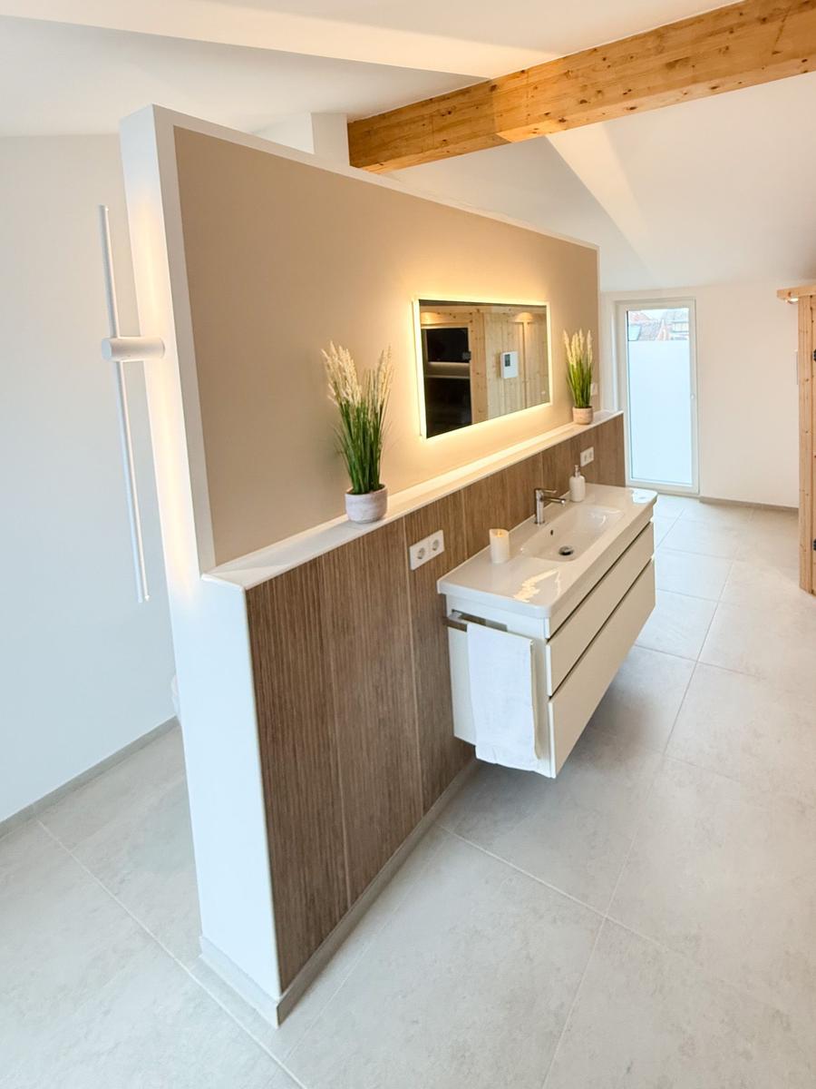 Modern bathtub with wood cladding and illuminated mirror
