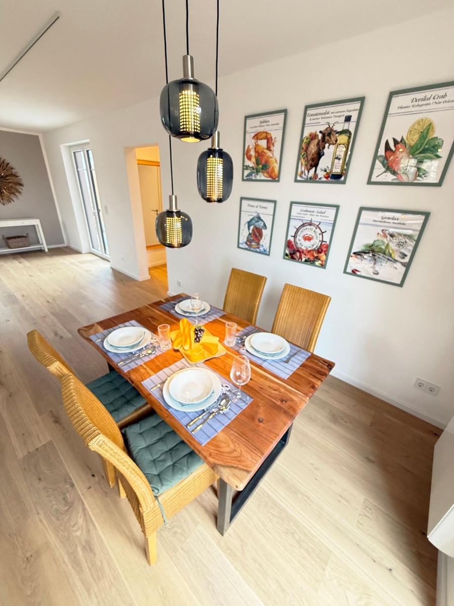 Dining table with four chairs and ceiling lights on the wall.