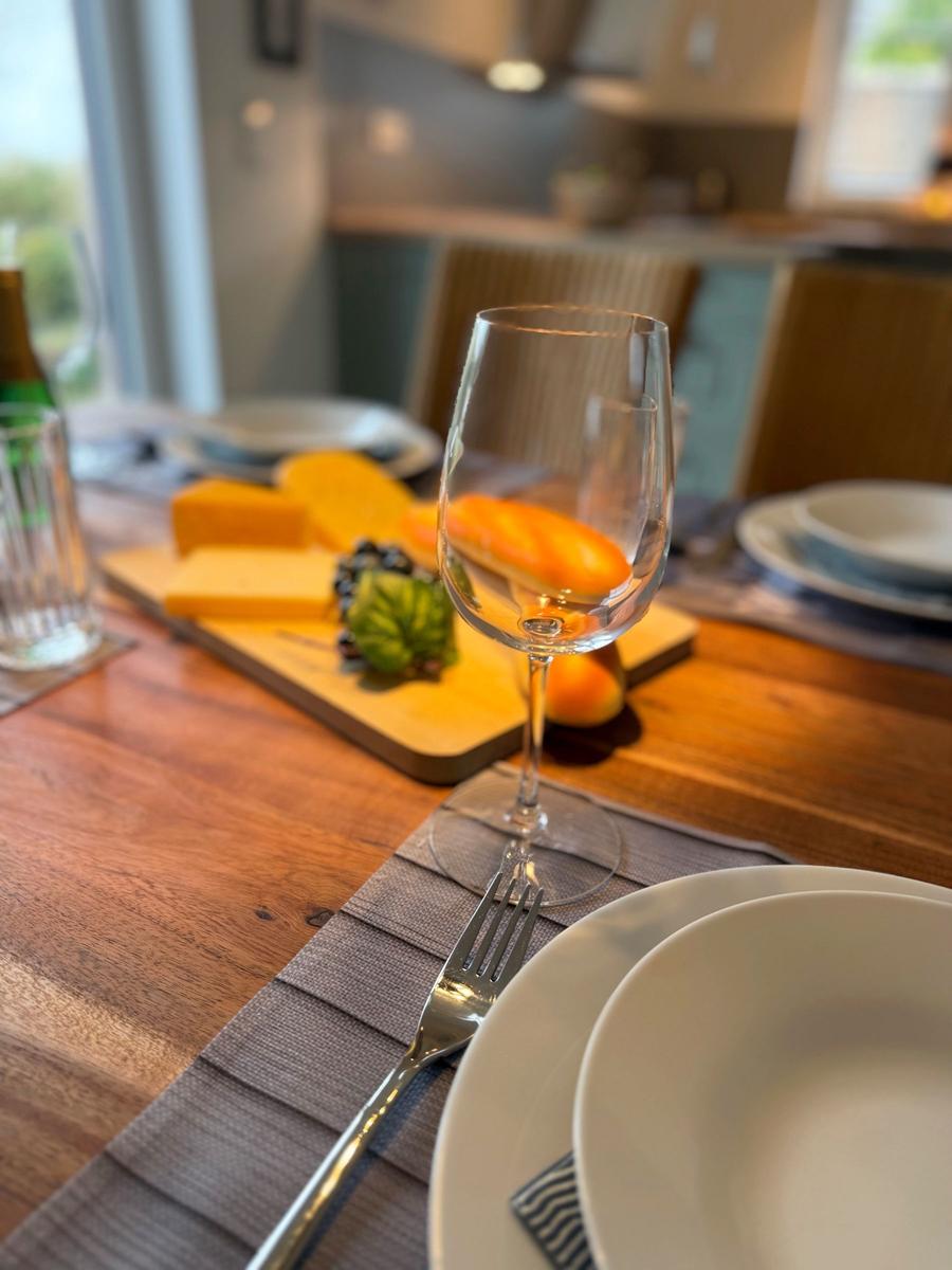 Set table with wine glass and cheese on wooden board