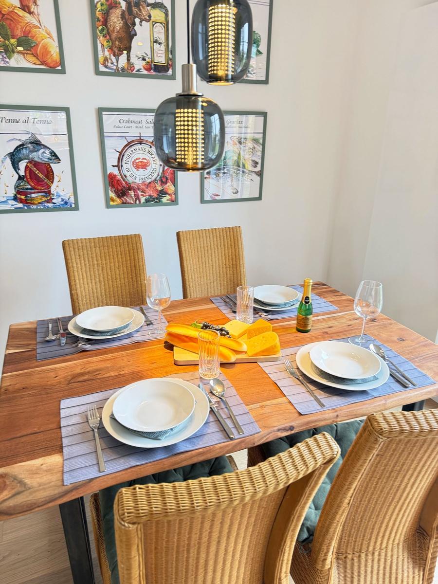 Wooden table with chairs, set with plates, cutlery, and bottle.