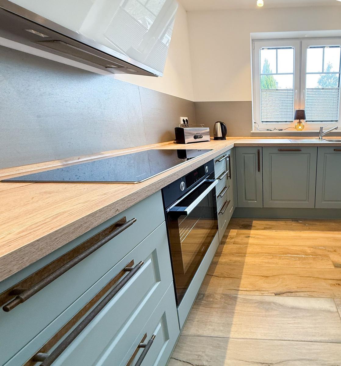Kitchen with wooden surfaces, light cabinets, and modern cooktop.