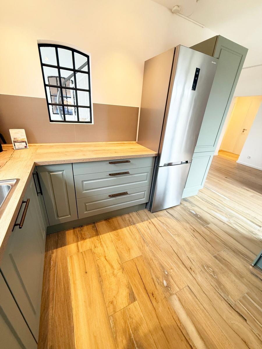 Kitchen with wooden floor, gray cabinets, and stainless steel refrigerator.