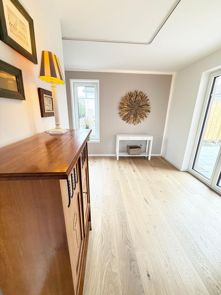 Entrance area with wooden floor, cabinet, table, and windows.