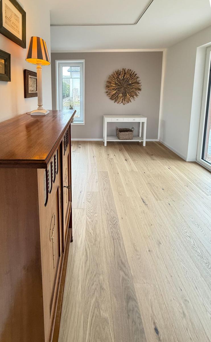 Bright entry hall with wooden floor, cabinet, and wall decoration.