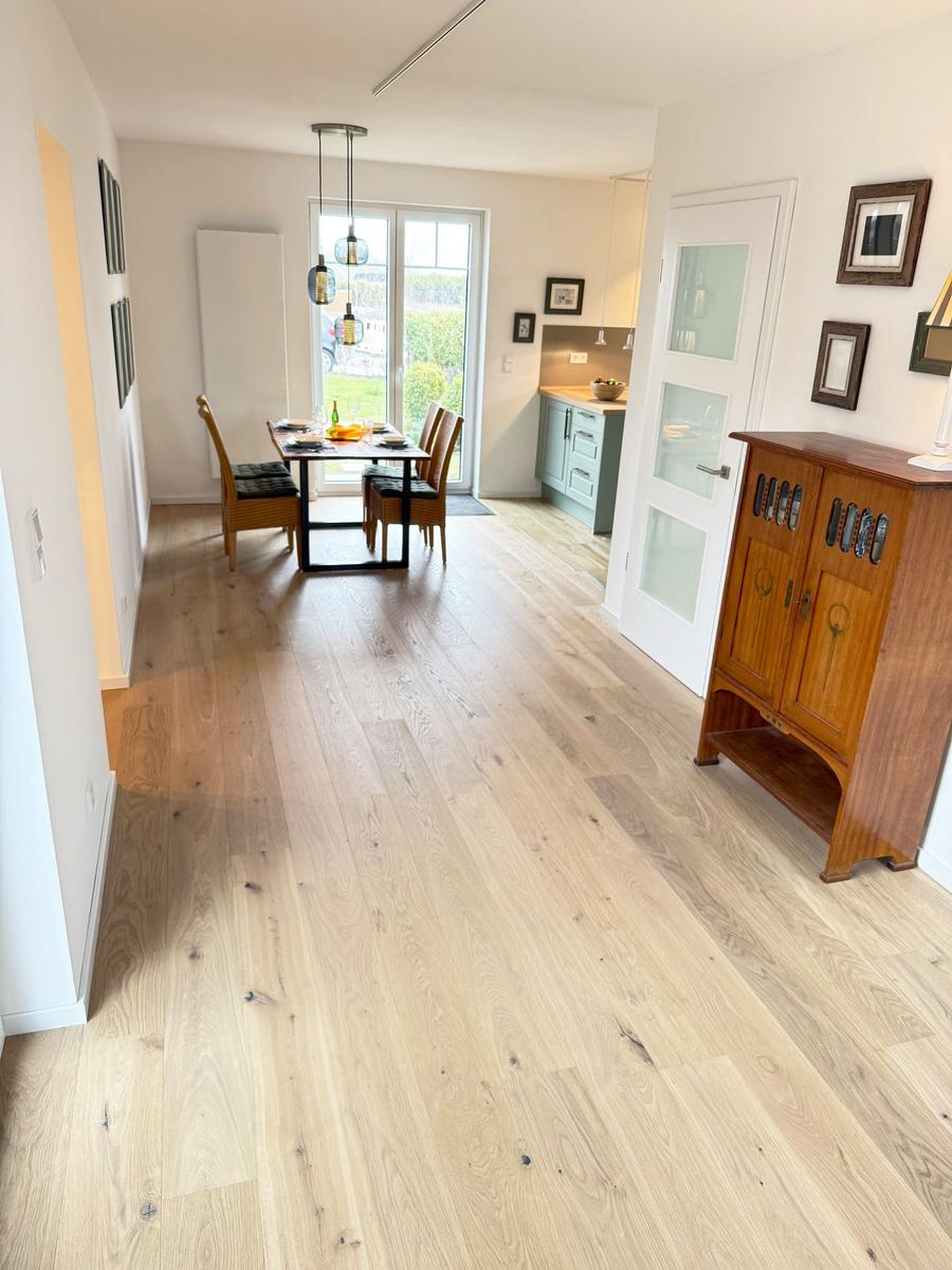 Entryway with wooden floor, dining area, and kitchen area.
