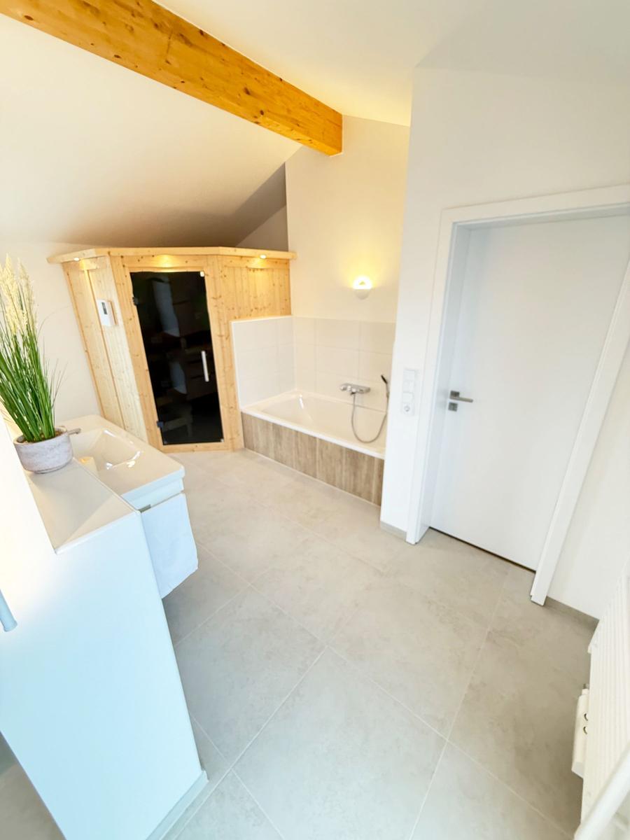 Bathroom with bathtub, shower, and wooden sauna