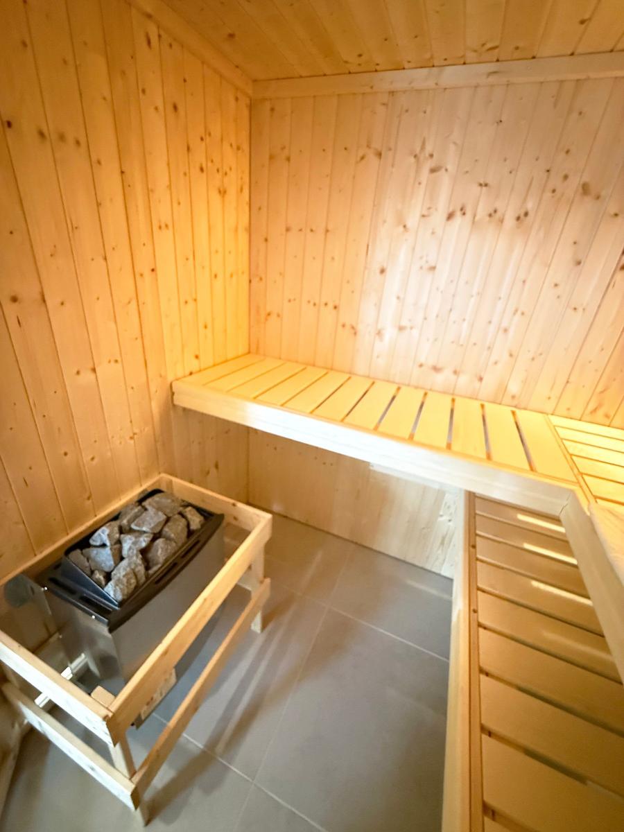 Sauna with wooden walls, bench, and stone heater.