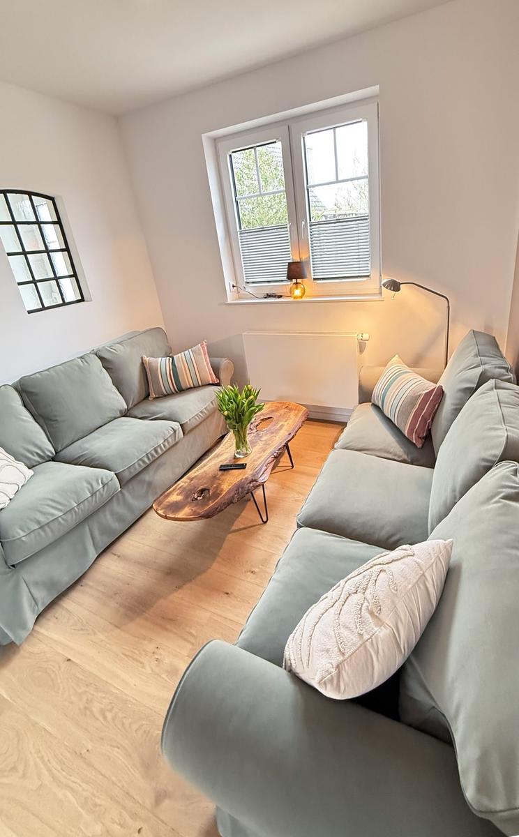 Living room with gray sofa, wooden table, and window