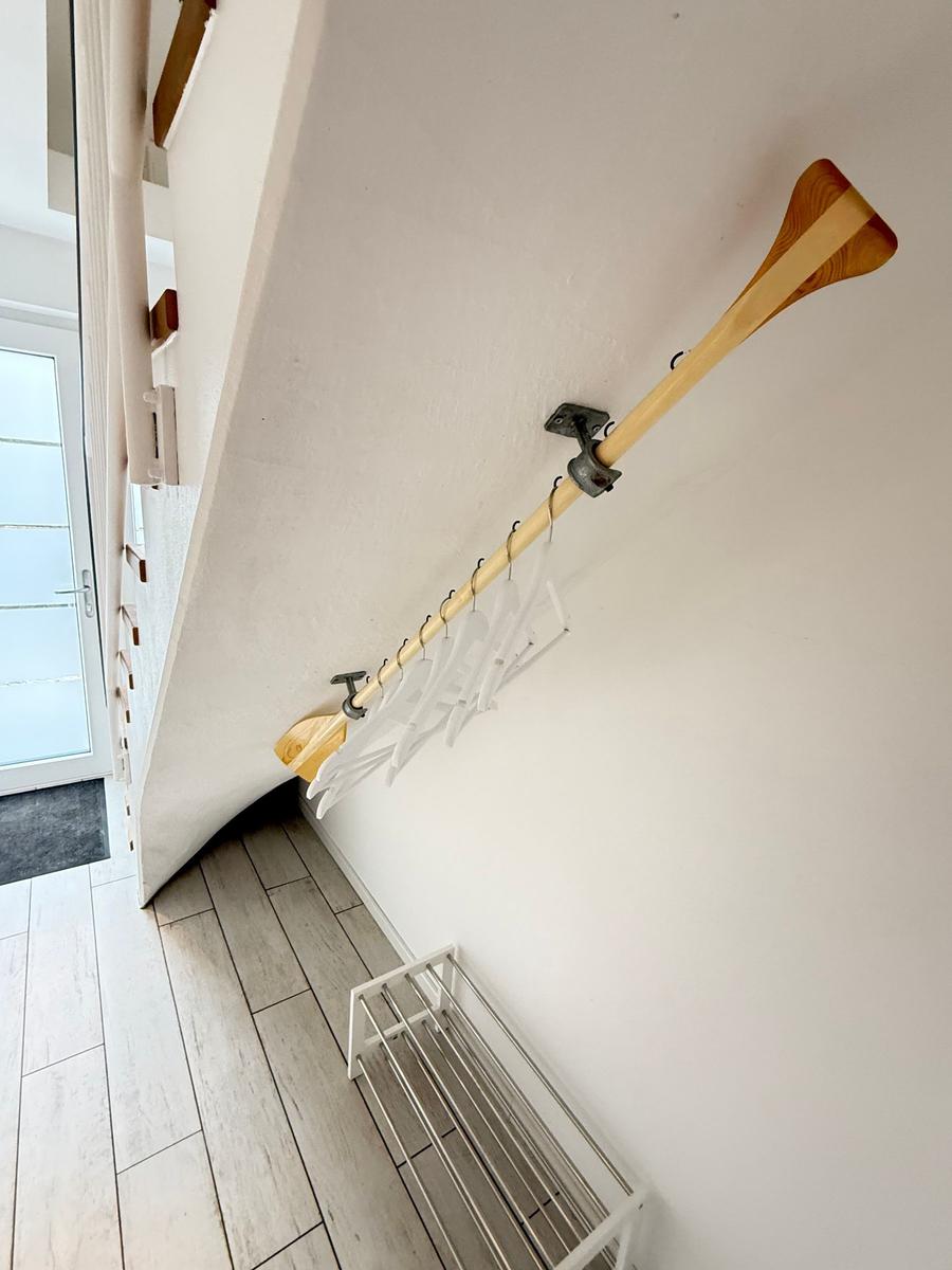 Wall-mounted rack with hooks and wooden pole for clothing