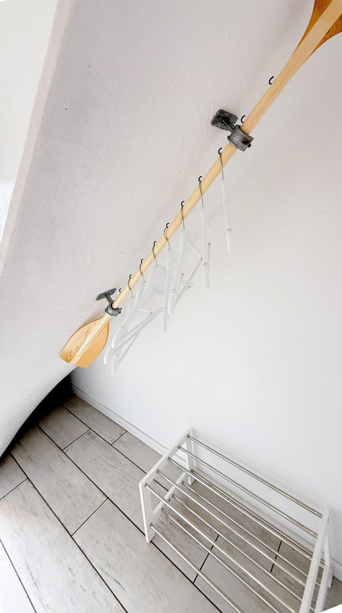 Clothes hanger system with wooden paddle mounted on wall