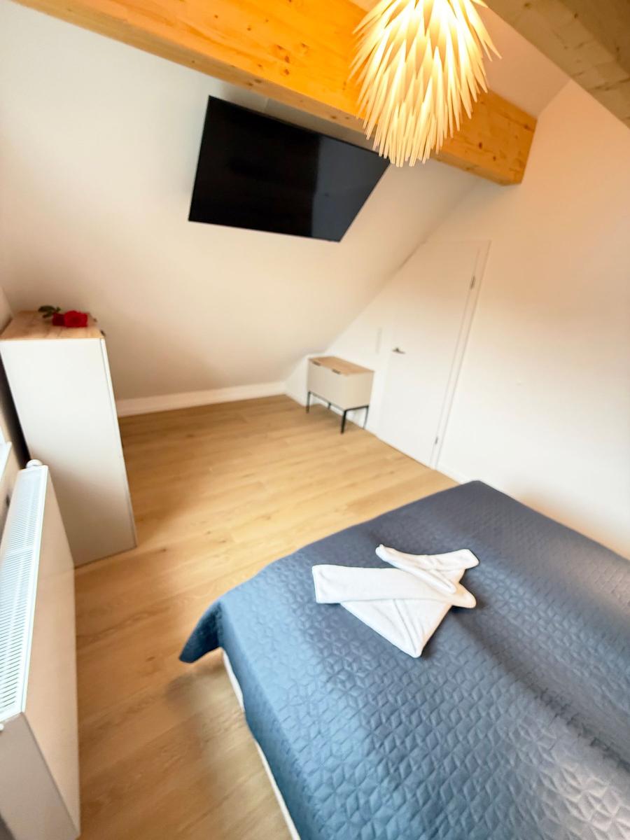 Bedroom with bed, TV, and wooden floor