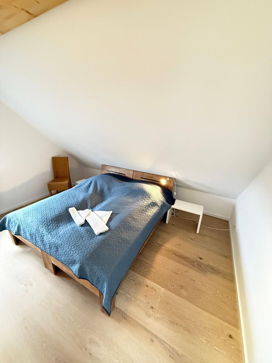 Bedroom with wooden floor, bed, and nightstand