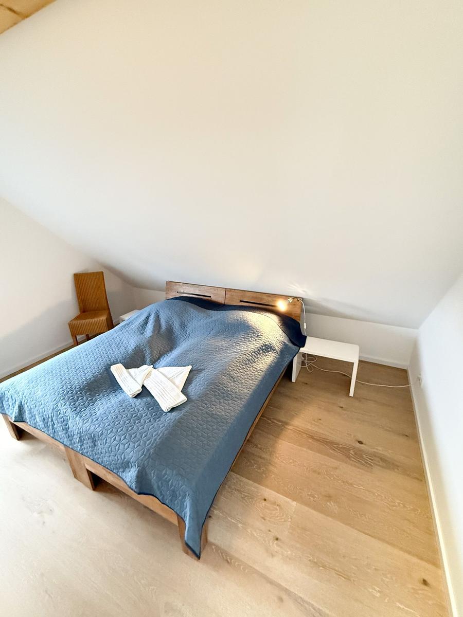 Bedroom with bed, nightstand, and chair under sloped ceiling