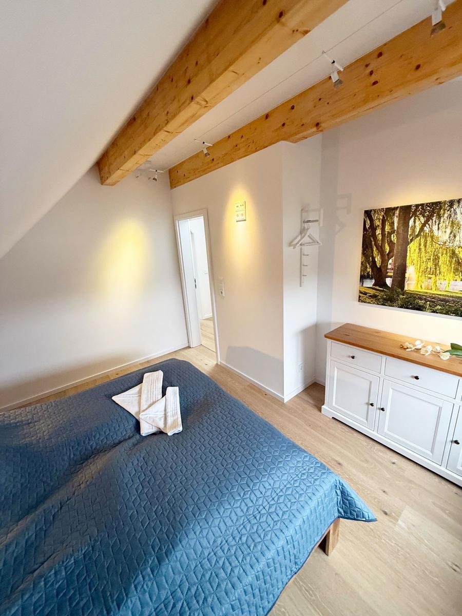 Bedroom with wooden beams, bed, and dresser.