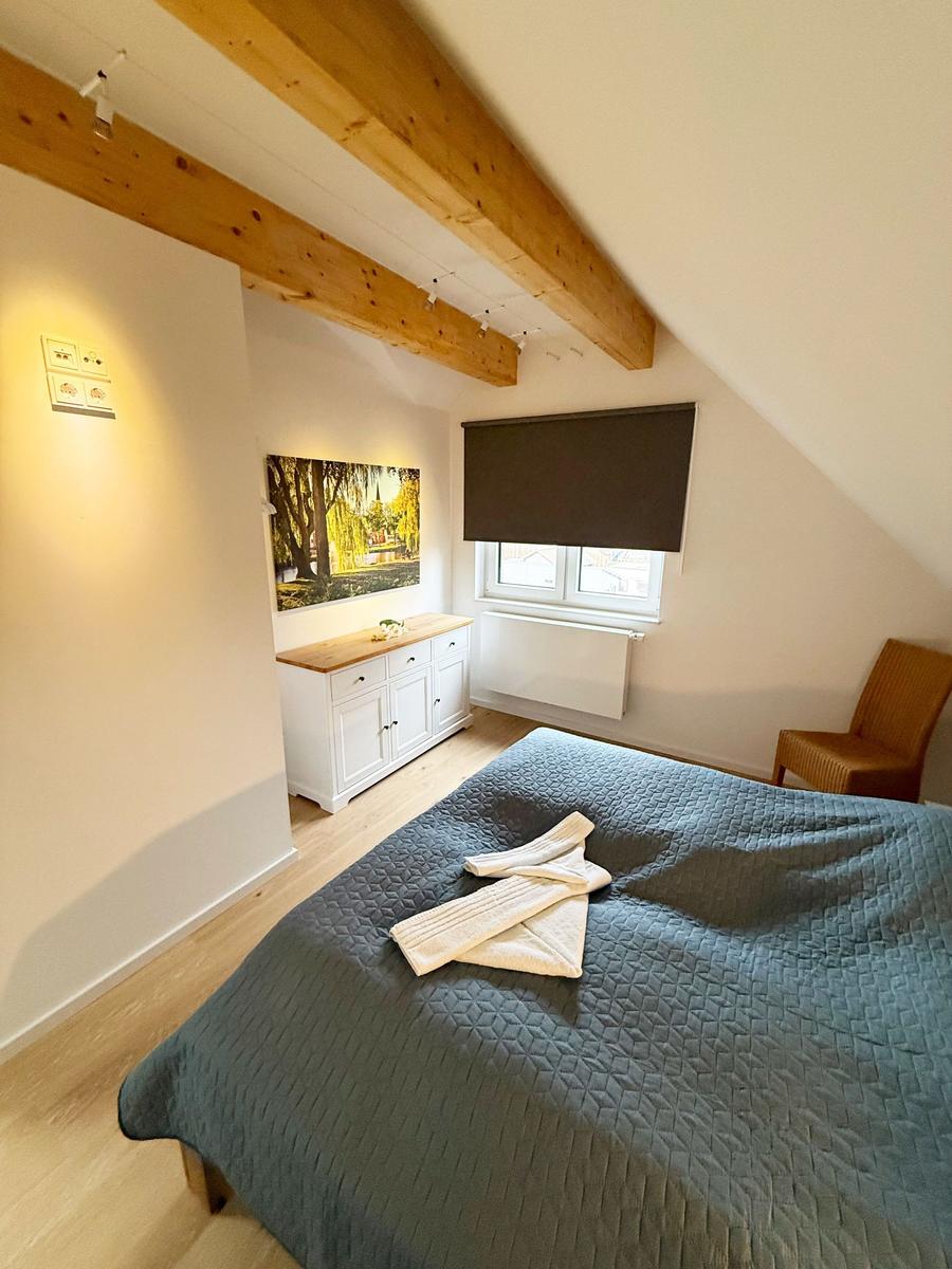 Bedroom with sloped ceiling, bed, dresser, and window.