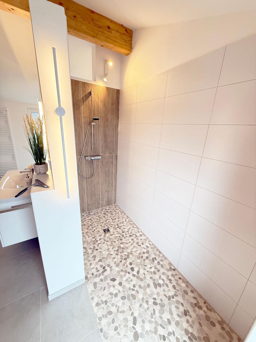 Shower with wooden wall, sink and mosaic floor