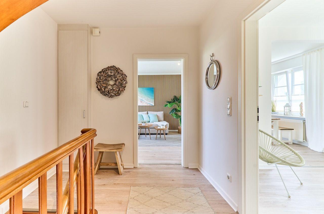 Hausgang mit Holzgeländer, Wanddekoration und Blick in Wohn- und Essbereich.