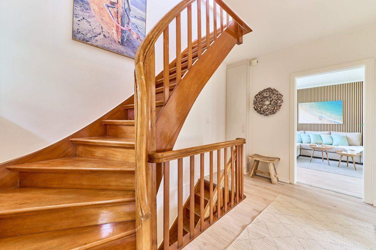 Holzgetreppe führt in Wohnbereich mit Sofa und Wandbild.