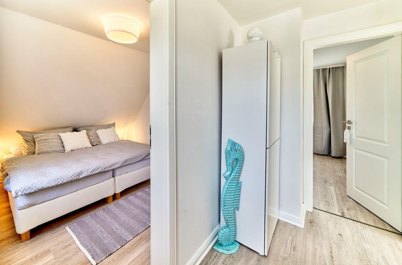 Schlafzimmer mit Bett, Teppich und Decke. Flur mit Kleiderschrank und Seepferdchen-Dekoration.