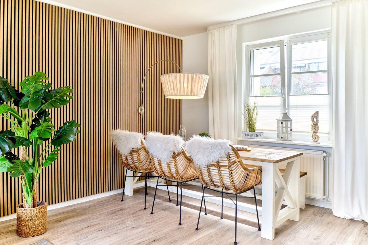 Esszimmer mit Holzwand, Esstisch und Stühlen mit Fellkissen.