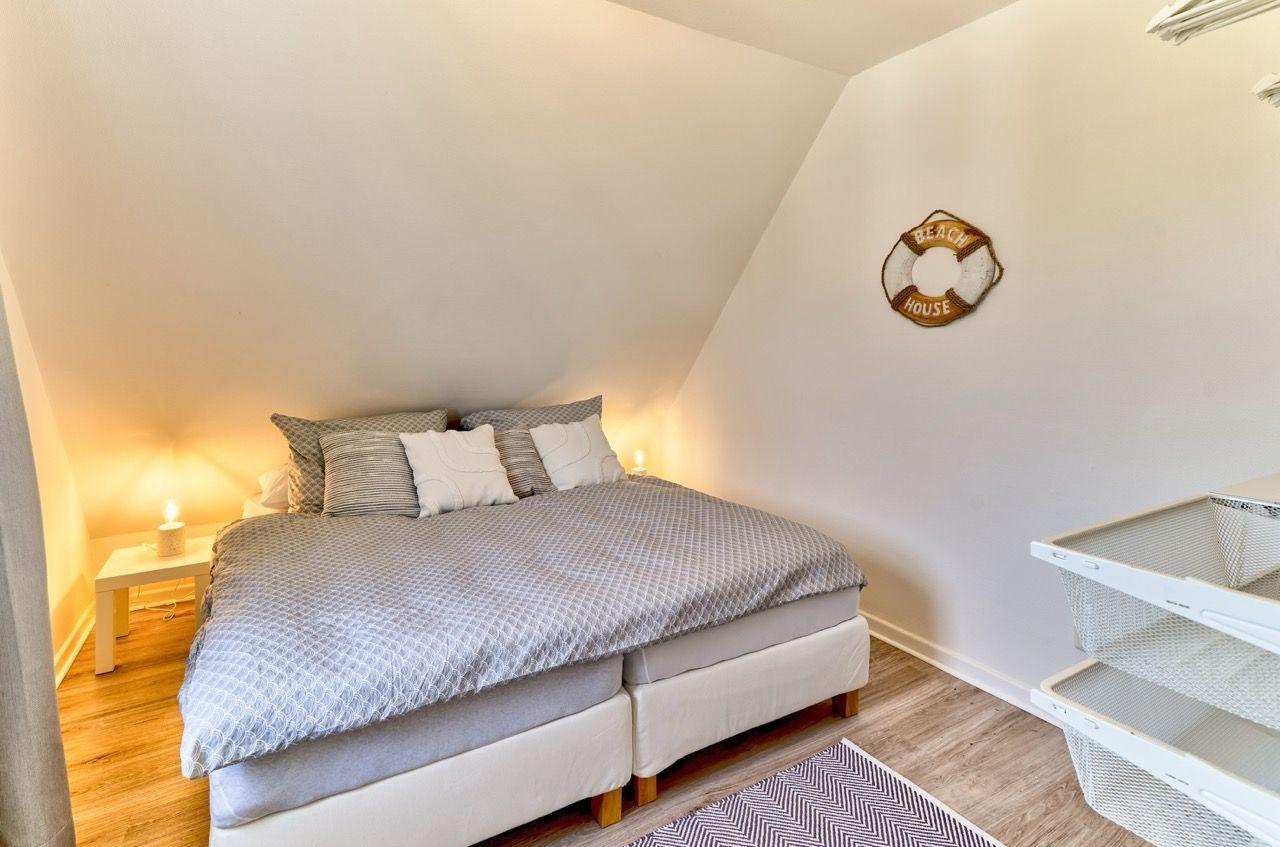 Schlafzimmer mit Doppelbett, Nachttisch und Wanddekoration.