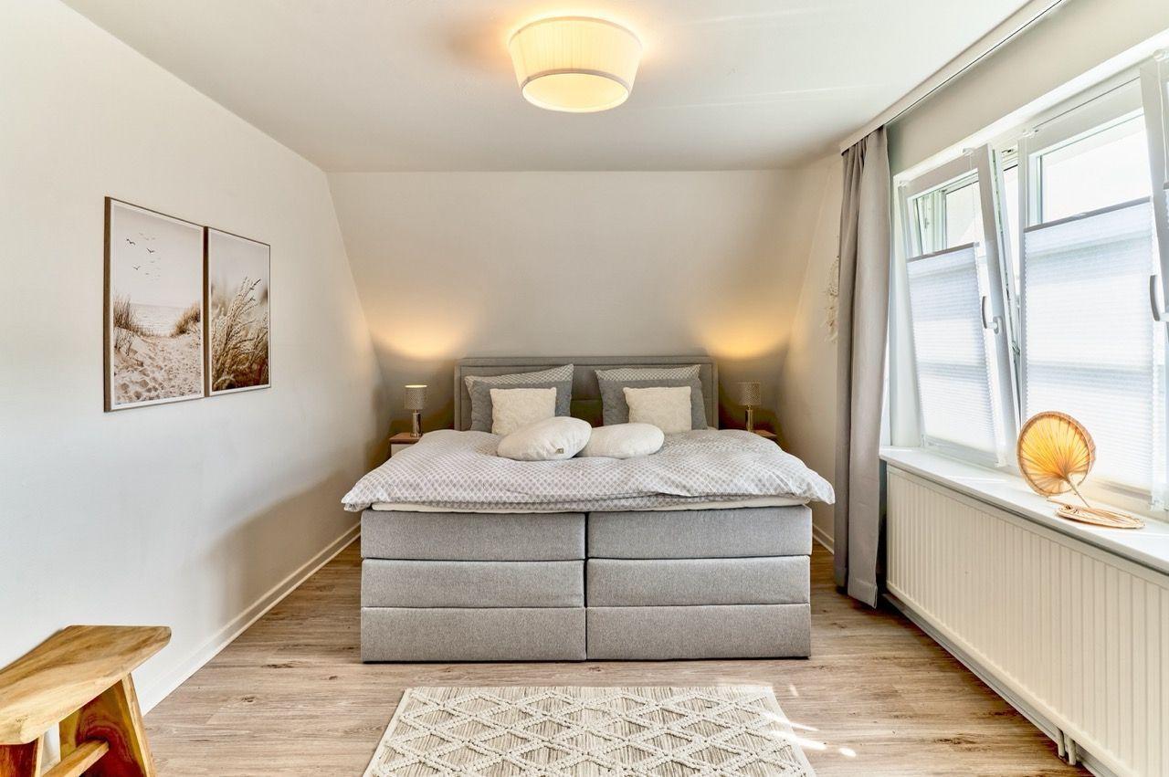 Schlafzimmer mit Bett, Fenster und Wandbildern.