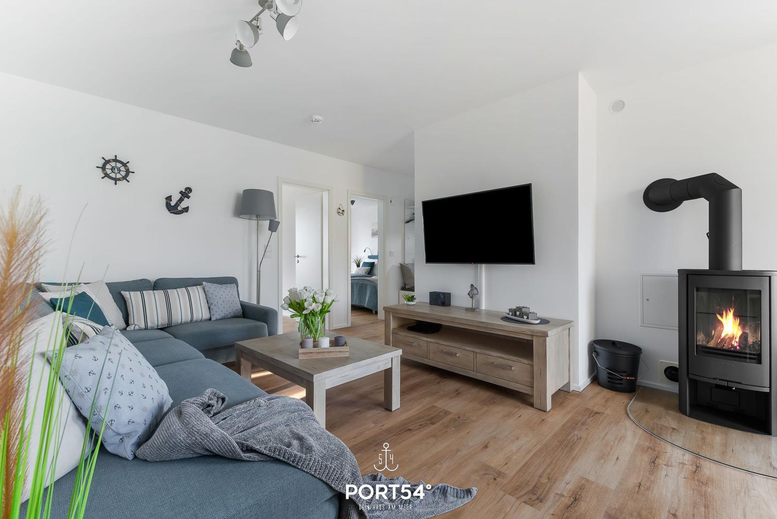 Wohnzimmer mit Sofa, Fernseher und Kaminofen.
