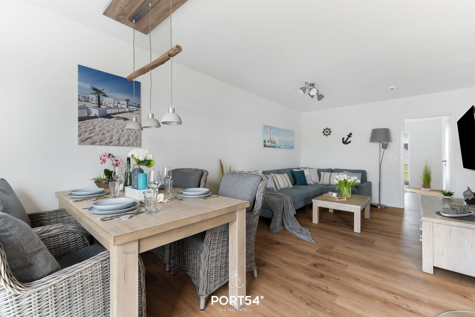 Essbereich mit Tisch und Stühlen. Wohnbereich mit Sofa und Couchtisch.
