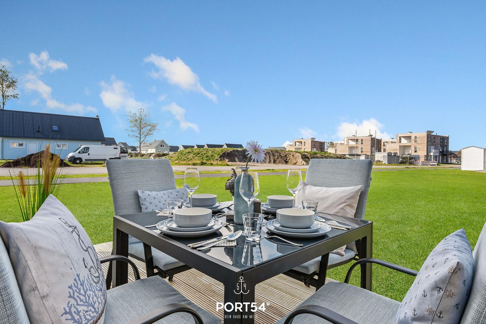 Garten-Terrasse mit Tisch und Stühlen, Blick auf Gras und Häuser