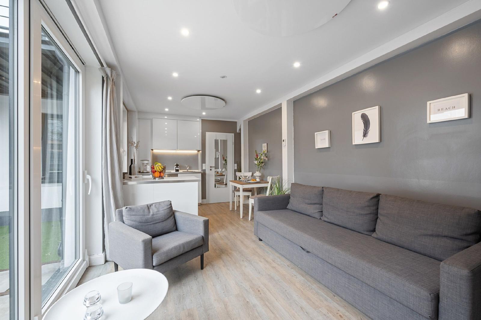 Wohn- und Essbereich mit Sofa, Sessel und Küchenzeile.