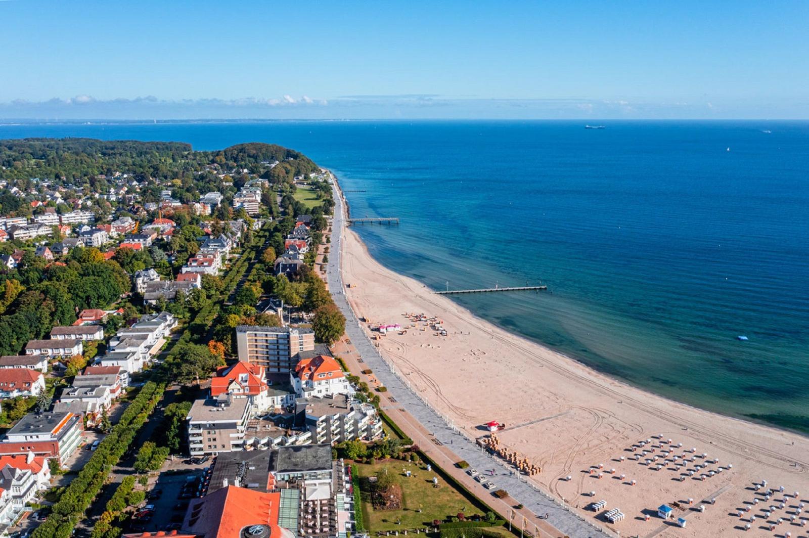 Strandpromenade mit Hotels und Strand. Blick aufs Meer und grüne Landschaft.