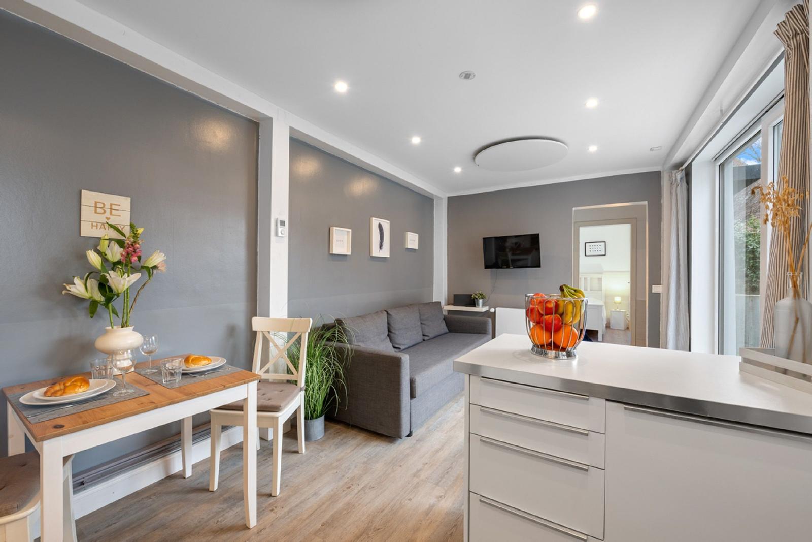 Wohn- und Essbereich mit Sofa, Tisch und Kücheninsel.