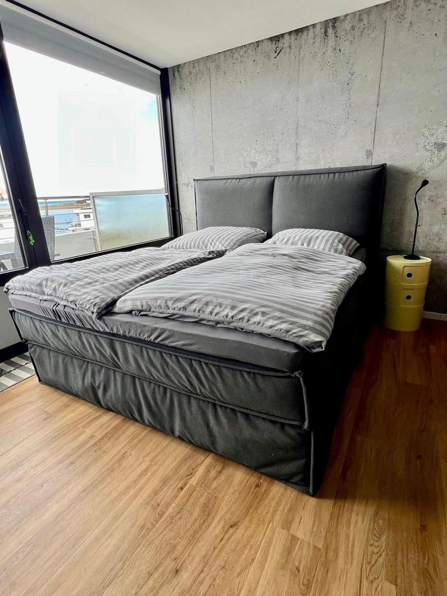 Schlafzimmer mit großem Bett, Holzboden und großer Fensterfront.